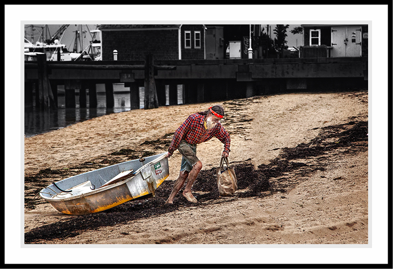 Fisherman pulling boat along the sand.